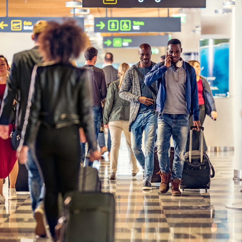 Travellers arriving through an airport terminal with their luggage